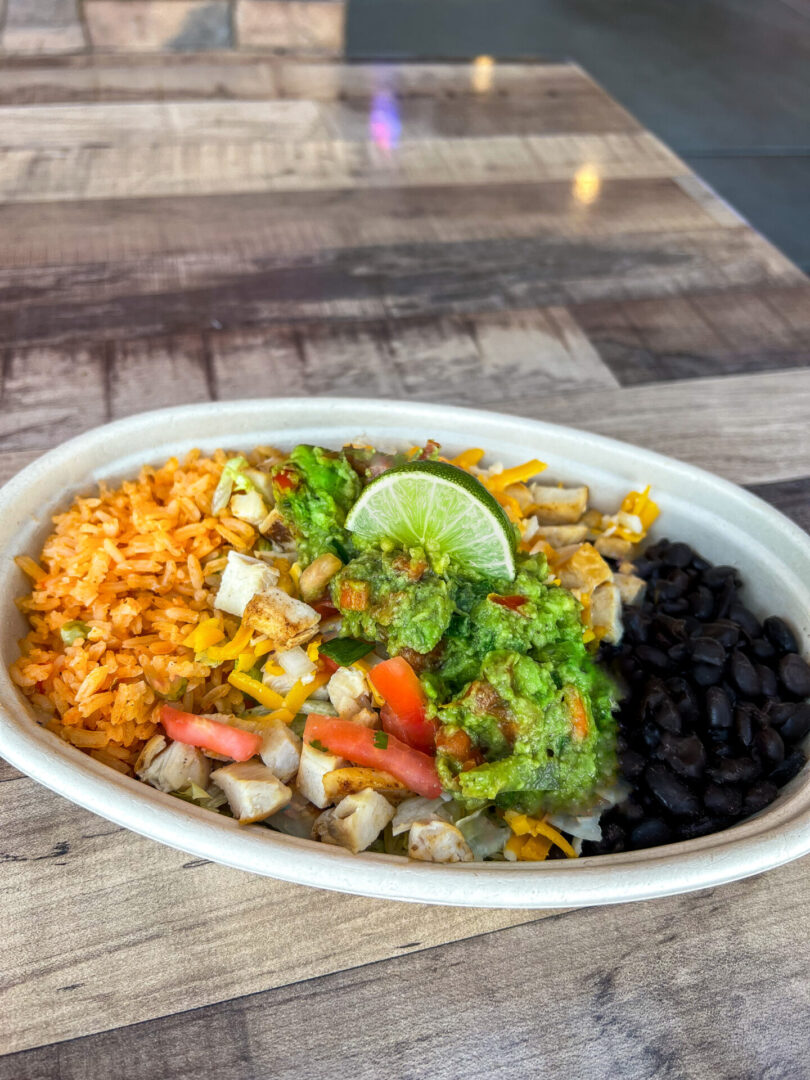 A bowl of rice, beans and vegetables on top of a table.